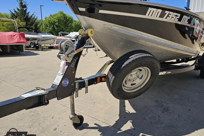 Slide: The Image of 2014 Alumacraft Classic 165 boat on trailer, parked outdoors in a sunny setting. - 13