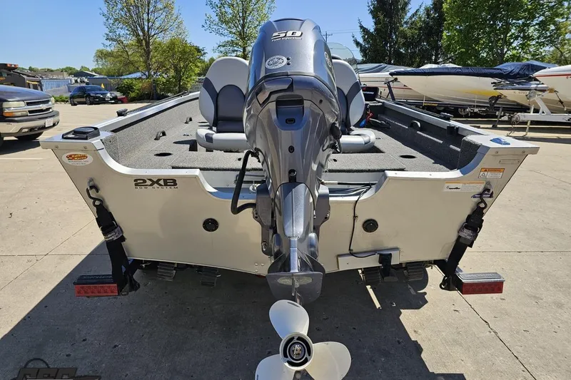 Slide: The Image of 2014 Alumacraft Classic 165 boat with outboard motor, parked outdoors on a sunny day. - 27