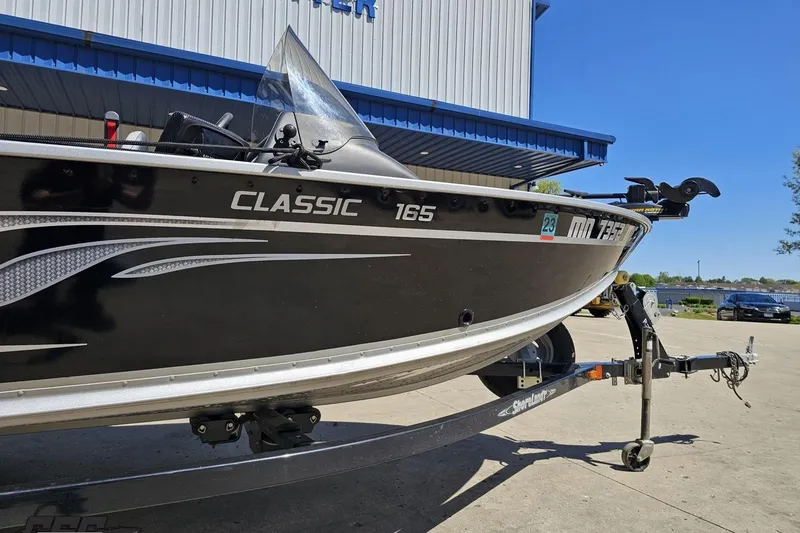 Slide: The Image of 2014 Alumacraft Classic 165 boat on trailer, parked outside a building. - 3