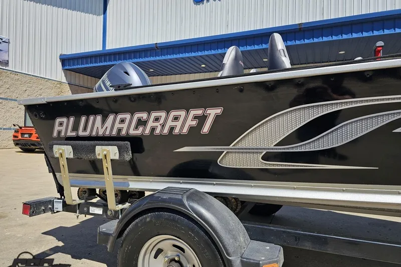 Slide: The Image of 2014 Alumacraft Classic 165 boat on trailer, parked outside a building. - 4