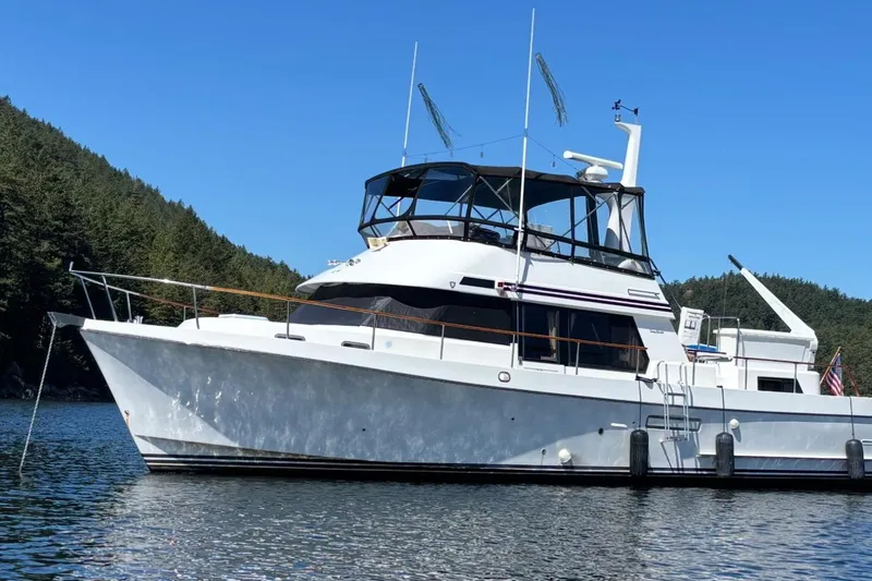 The Image of 1992 Ocean Alexander 456 Classicco yacht anchored in scenic waters with forested backdrop. - 0
