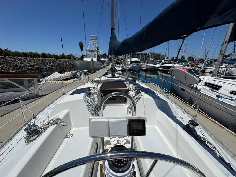 Slide: The Image of Hunter Legend 375 sailboat from 1992 docked at a marina, showcasing cockpit and steering wheel. - 10