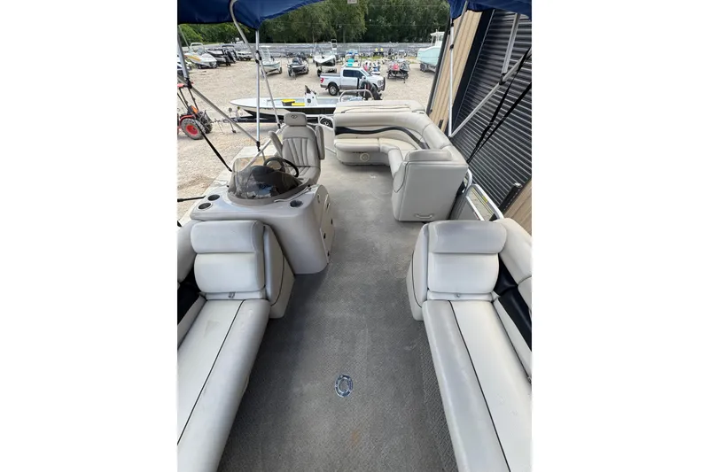 Slide: The Image of 2011 Veranda Tritoon boat interior with spacious seating and helm, parked in a marina. - 17