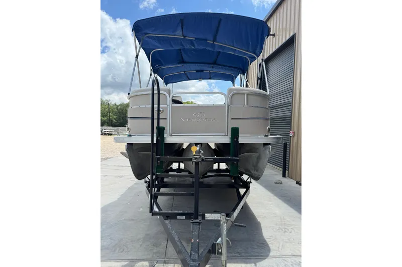 Slide: The Image of 2011 Veranda Tritoon boat with blue canopy on trailer, parked outdoors. - 21