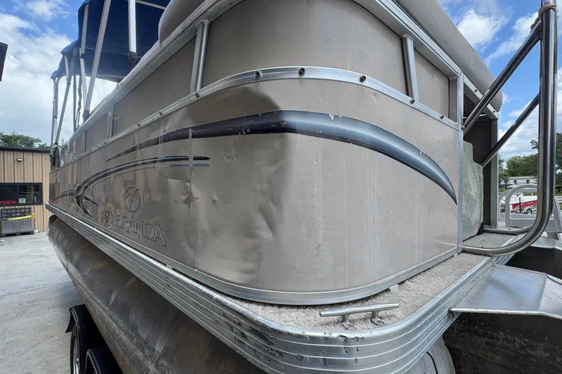 Slide: The Image of 2011 Veranda Tritoon boat with visible wear, parked outdoors under a blue sky. - 4