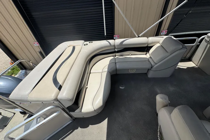 Slide: The Image of 2011 Veranda Tritoon boat with beige seating and sleek design, docked near a building. - 8