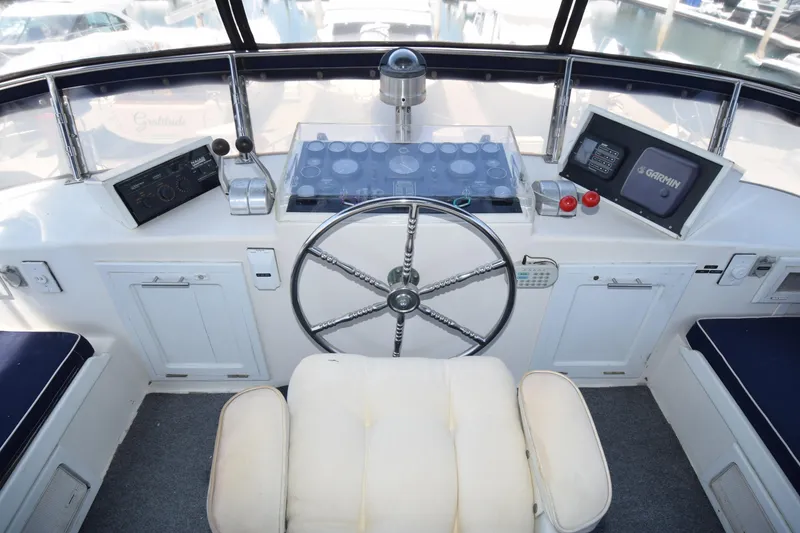 Slide: The Image of 1988 Sea Ranger 51 Motor Yacht helm with steering wheel, navigation instruments, and cushioned seat. - 16