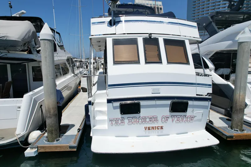 Slide: The Image of 1988 Sea Ranger 51 Motor Yacht docked at marina, rear view with "The Broker of Venice" text. - 23
