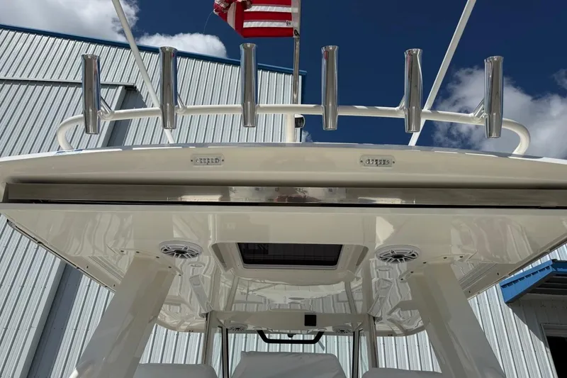 Slide: The Image of 2026 Pursuit S 358 Sport boat with rod holders and American flag, under clear sky. - 23