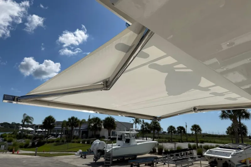 Slide: The Image of 2026 Pursuit S 358 Sport boat with extended sunshade under a clear blue sky. - 24