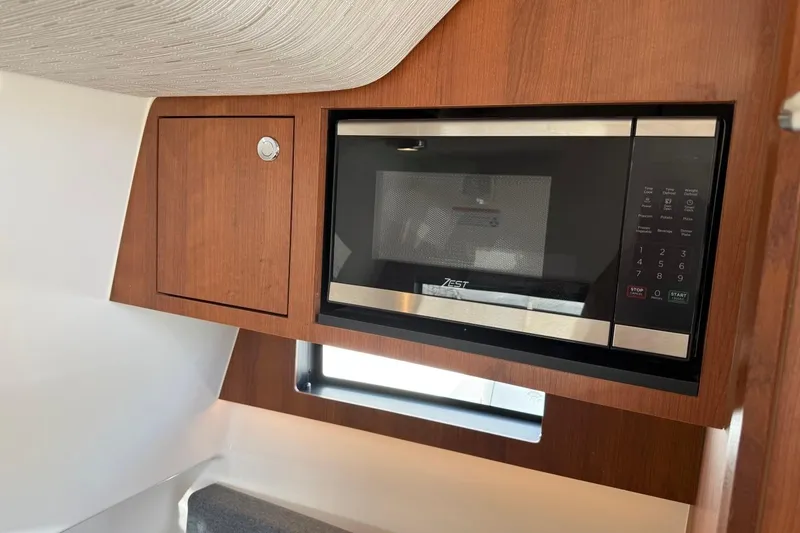 Slide: The Image of Microwave in 2026 Pursuit S 358 Sport boat interior, featuring sleek wood cabinetry. - 56
