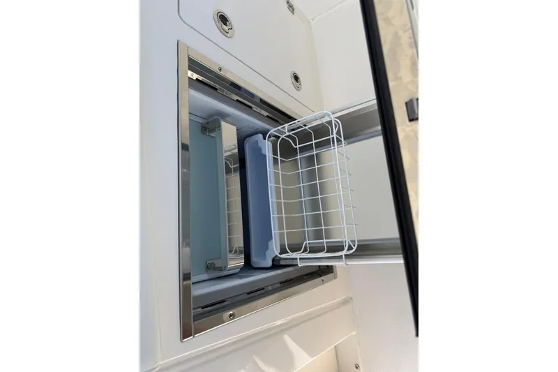 Slide: The Image of Built-in storage compartment on 2026 Pursuit S 358 Sport boat, featuring a sliding wire basket. - 61