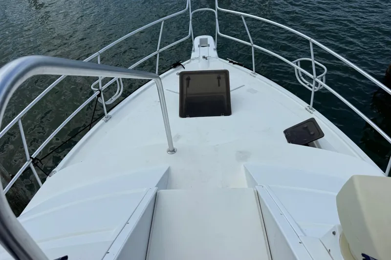 Slide: The Image of 1995 Mainship 37 Motor Yacht bow view with railing and hatch, docked on water. - 17