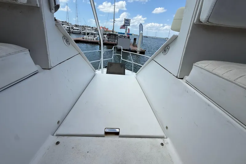 Slide: The Image of 1995 Mainship 37 Motor Yacht deck view at marina, showcasing seating and water backdrop. - 18