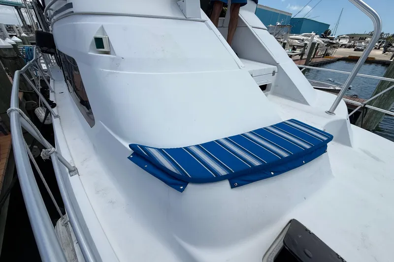 Slide: The Image of 1995 Mainship 37 Motor Yacht with blue-striped cushion on deck, docked at marina. - 23