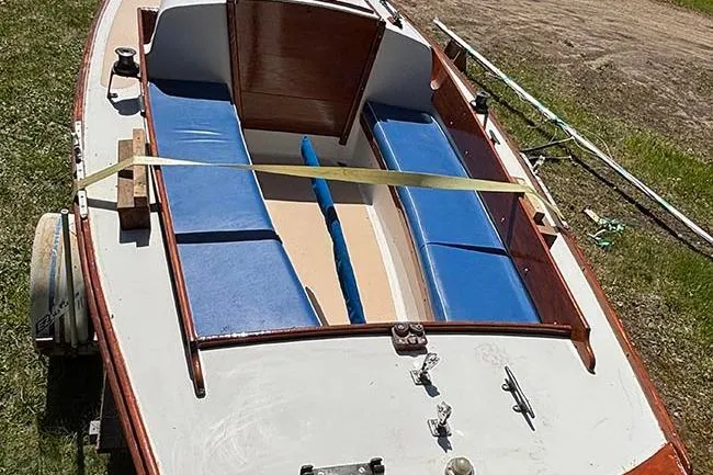 Slide: The Image of 1977 Cape Dory Typhoon Weekender sailboat with blue seating and wooden accents on grass. - 4