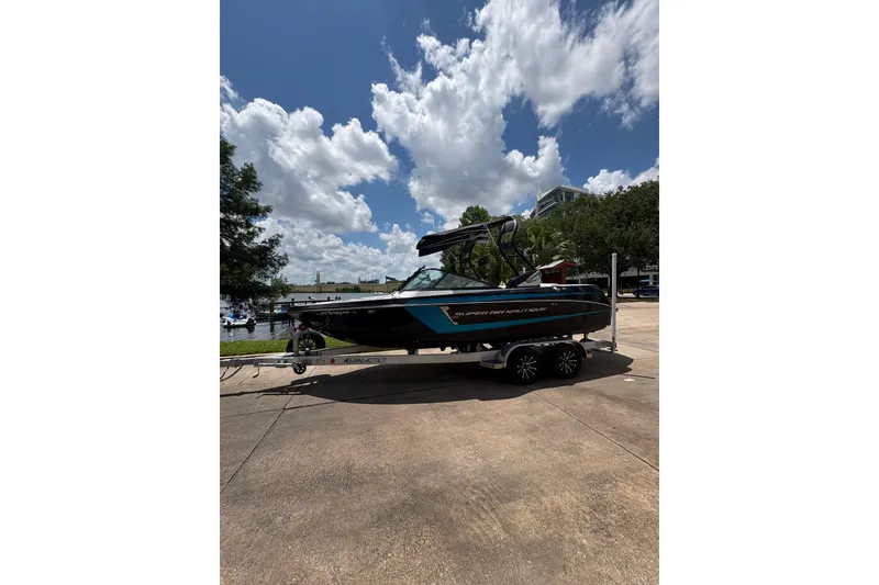 Slide: The Image of 2014 Nautique Super Air Nautique 210 boat on trailer under a partly cloudy sky. - 1