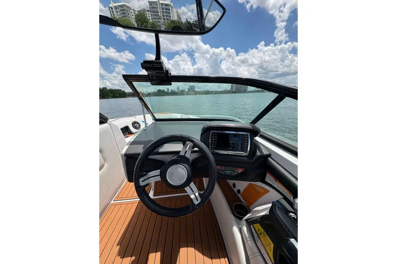 Slide: The Image of 2014 Nautique Super Air Nautique 210 boat cockpit with steering wheel and digital display. - 4