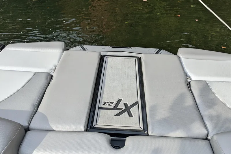 Slide: The Image of 2018 MasterCraft XT23 boat interior with cushioned seating near water. - 5