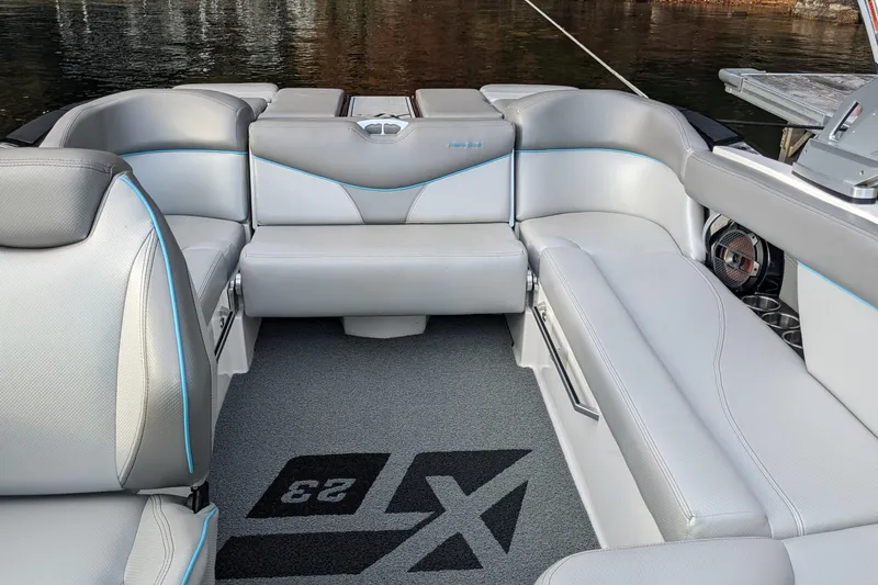 Slide: The Image of 2018 MasterCraft XT23 boat interior with gray seating and blue accents on the water. - 9