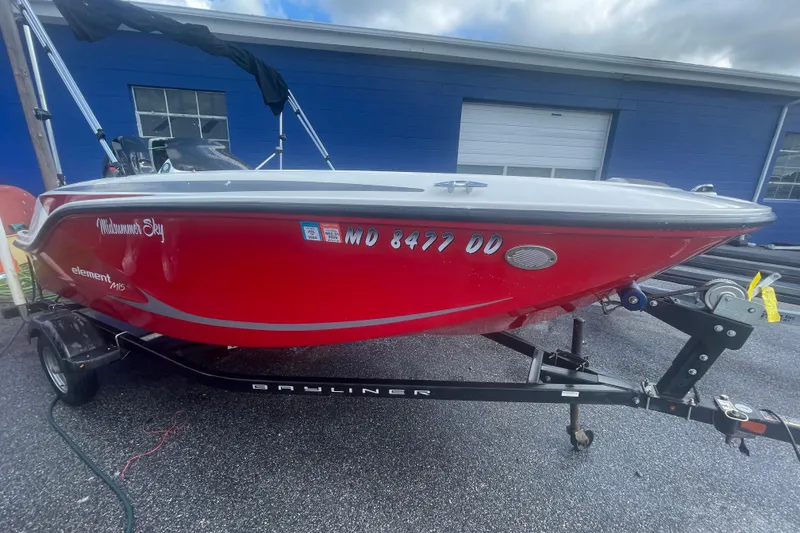 The Image of 2022 Bayliner Element M15 boat in vibrant red on a trailer, parked outdoors. - 0