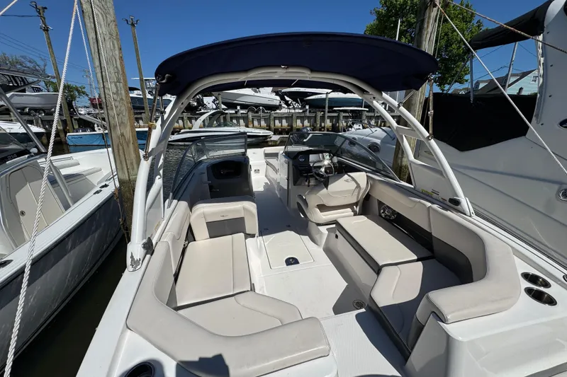 Slide: The Image of 2018 Chaparral 250 Suncoast boat interior with seating and steering wheel, docked at marina. - 4