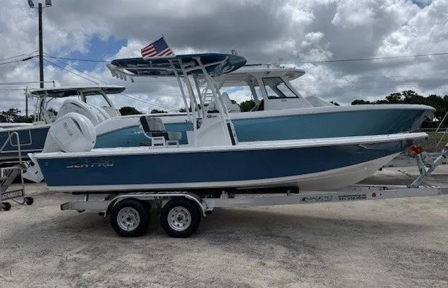 The Image of 2026 Sea Pro 230DLX boat on trailer, blue hull, American flag. - 1