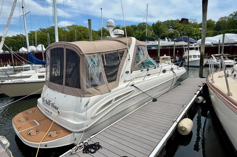 Slide: The Image of 2003 Sea Ray 340 Sundancer docked at marina, featuring tan canopy and sleek design. - 2