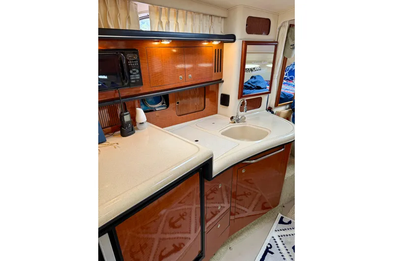Slide: The Image of 2003 Sea Ray 340 Sundancer interior kitchen with sink, microwave, and wooden cabinetry. - 9