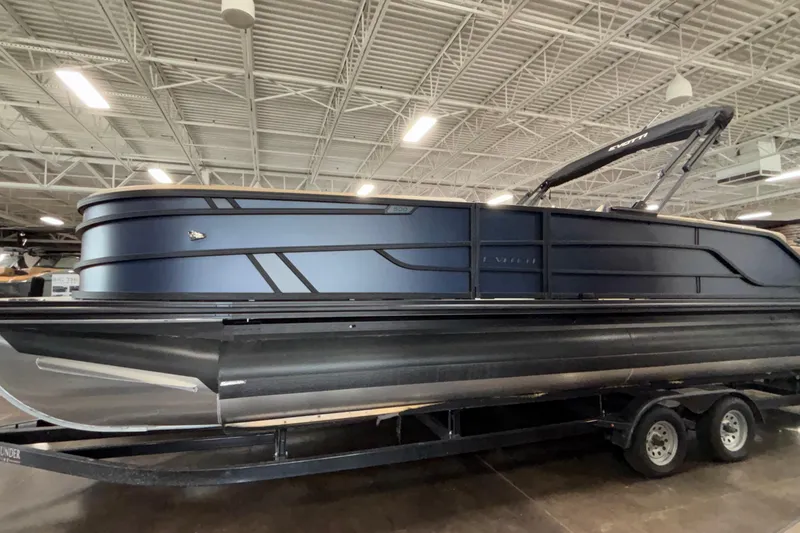 Slide: The Image of 2026 Evotti 525QL pontoon boat in showroom, sleek design, dark blue exterior. - 2
