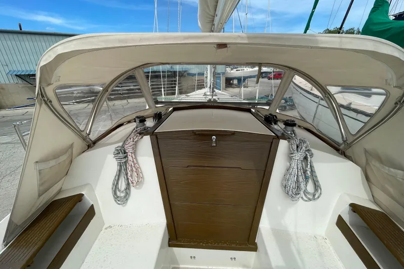 Slide: The Image of 1988 Catalina 30 sailboat cockpit with ropes and wooden hatch under a clear blue sky. - 12