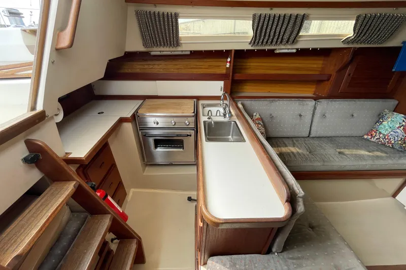 Slide: The Image of Interior of a 1988 Catalina 30 sailboat featuring a compact kitchen and seating area. - 20