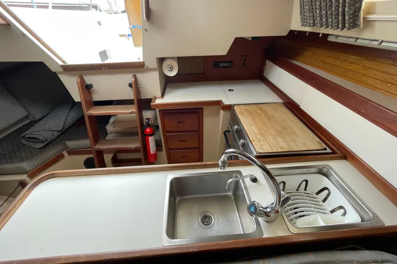 Slide: The Image of Interior of a 1988 Catalina 30 sailboat kitchen with sink, stove, and storage. - 21