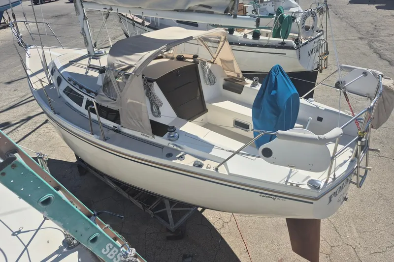 Slide: The Image of 1988 Catalina 30 sailboat on dry dock, featuring a spacious cockpit and protective canopy. - 9
