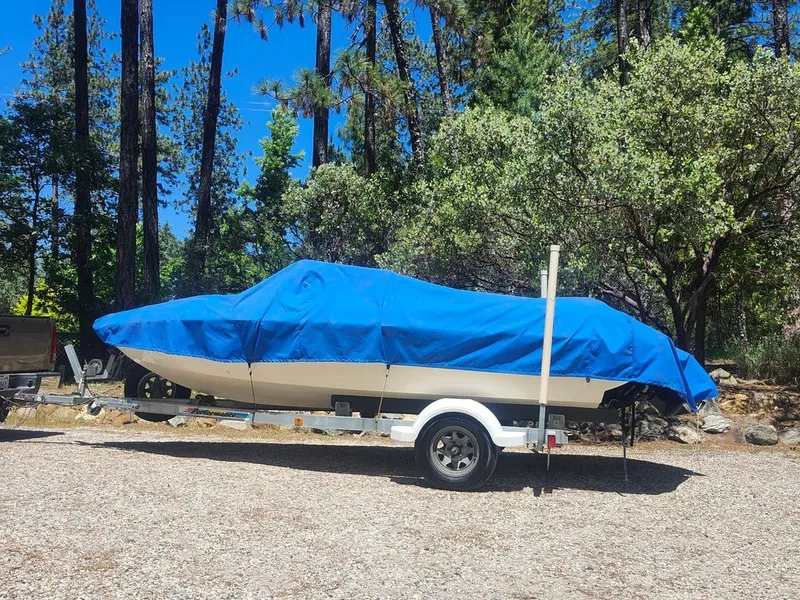 The Image of 1998 Stingray 180RS boat with blue cover in forest setting. - 0