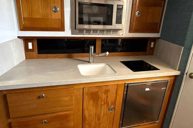 Slide: The Image of Compact yacht kitchen with wooden cabinets, sink, microwave, and stovetop in a 2000 Dawson Yachts Express. - 18