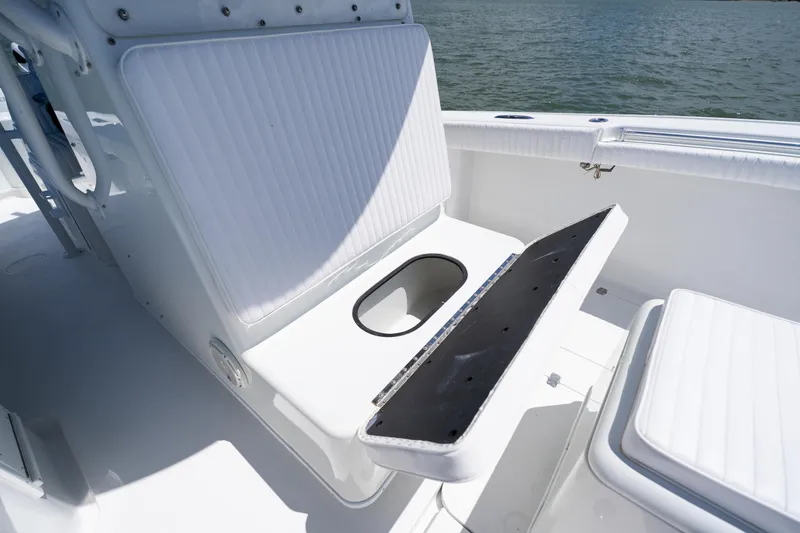 Slide: The Image of 2007 Yellowfin 34 Offshore boat interior with open storage compartment, white seating, and ocean backdrop. - 28