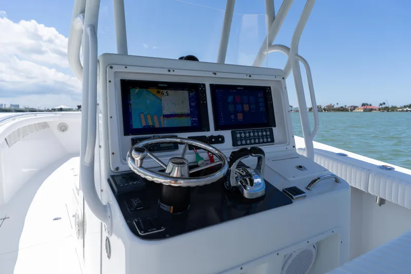 Slide: The Image of 2007 Yellowfin 34 Offshore boat dashboard with navigation screens and steering wheel on open water. - 33