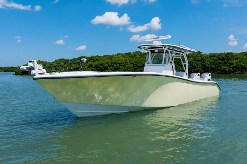 Slide: The Image of 2007 Yellowfin 34 Offshore boat on calm water, clear sky, lush greenery background. - 5