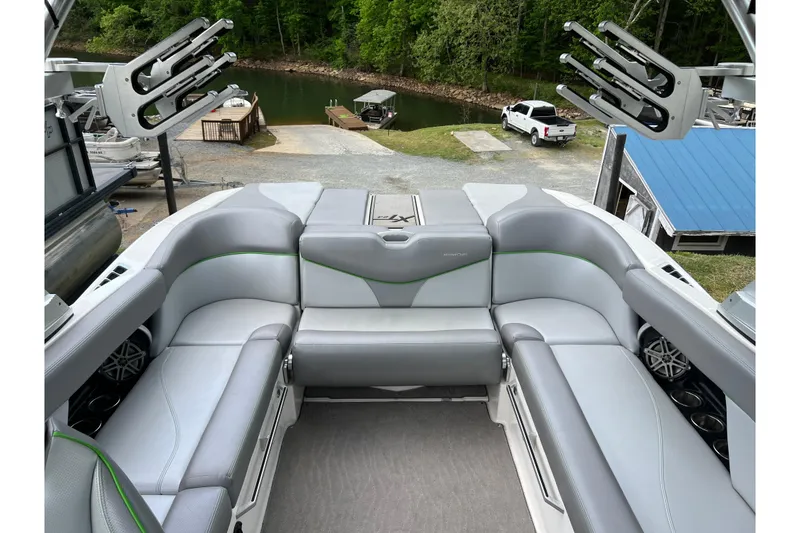 Slide: The Image of 2017 MasterCraft XT23 boat interior with gray seating and green accents, dockside view. - 2