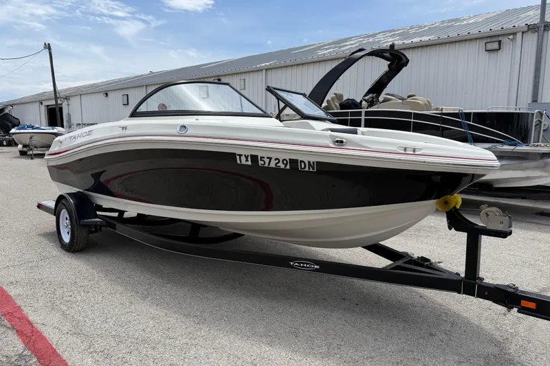 The Image of 2016 Tahoe 500 TF boat on trailer, parked outdoors near a warehouse. - 0