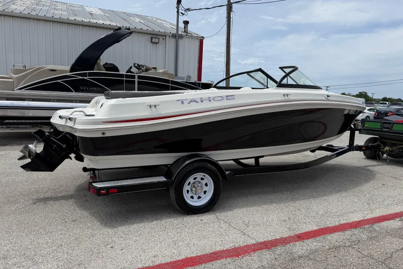 Slide: The Image of 2016 Tahoe 500 TF boat on trailer, parked outdoors near other boats. - 14
