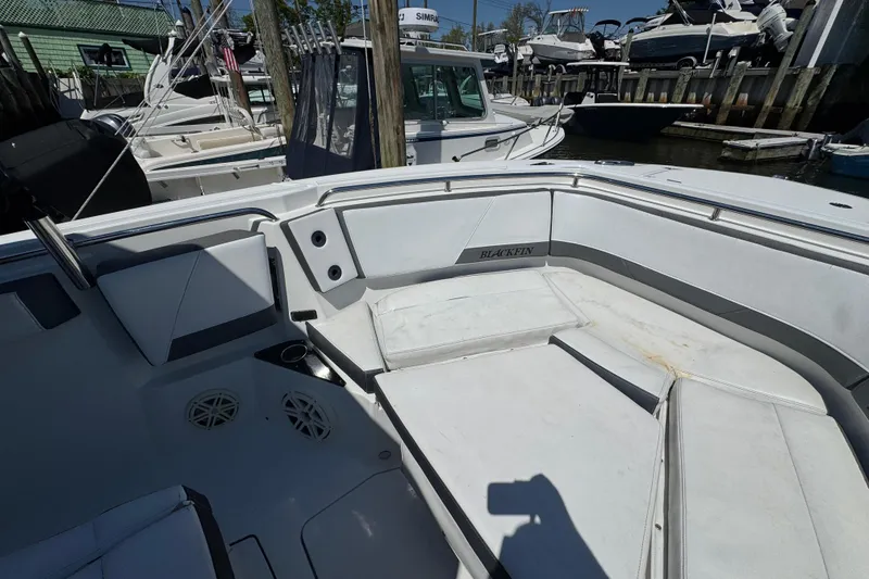 Slide: The Image of 2020 Blackfin 272 CC boat interior with white seating and cup holders at a marina. - 20