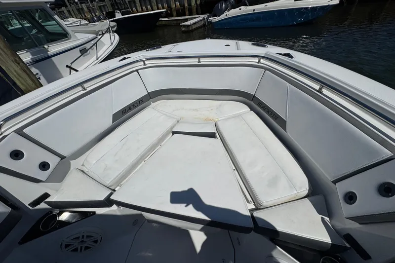 Slide: The Image of 2020 Blackfin 272 CC boat interior with cushioned seating at a marina. - 21