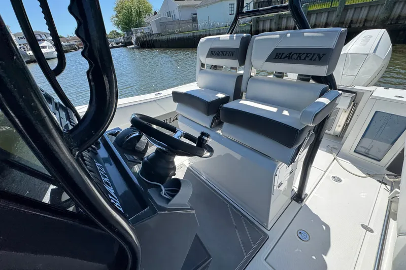 Slide: The Image of 2020 Blackfin 272 CC boat interior with dual seats and steering wheel, docked by the water. - 25