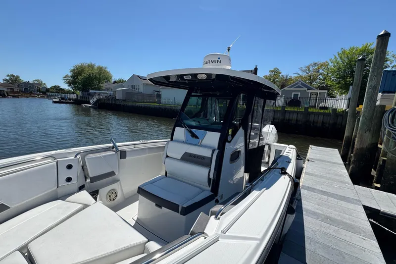 Slide: The Image of 2020 Blackfin 272 CC boat docked by a serene waterfront, featuring a Garmin navigation system. - 36