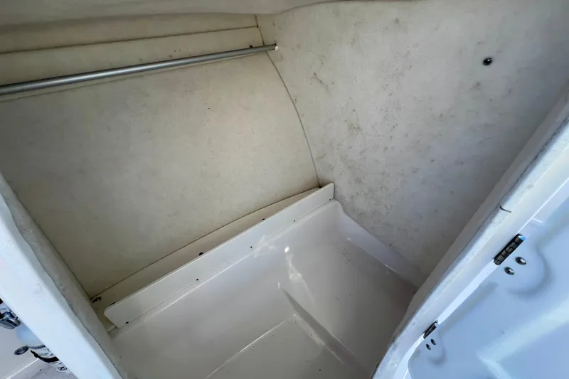 Slide: The Image of 2024 Robalo R207 Dual Console interior storage compartment, featuring clean white surfaces and a metal rod. - 19