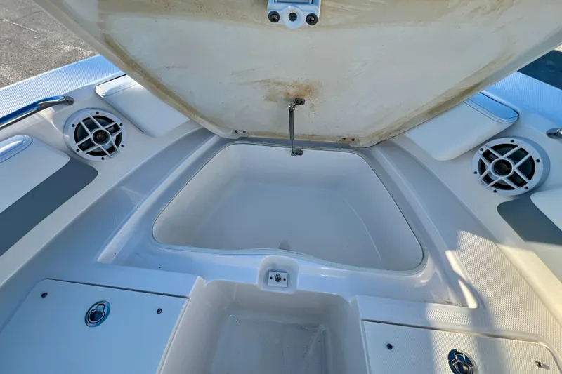 Slide: The Image of 2024 Robalo R207 Dual Console boat storage compartment with open hatch and speakers. - 21