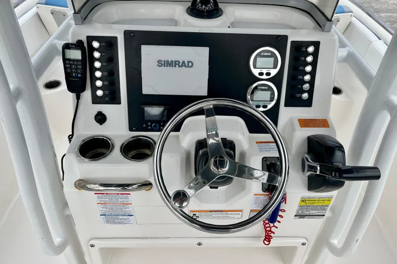 Slide: The Image of 2024 Robalo R222 Center Console dashboard with steering wheel, Simrad display, and Yamaha controls. - 13