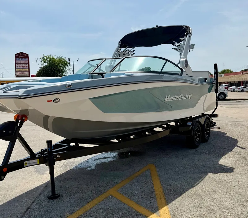Slide: The Image of 2026 MasterCraft XT24 boat parked on trailer outdoors. - 5